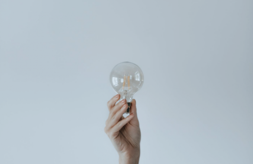 tech genius myth lightbulb being held in hand on plain white background 