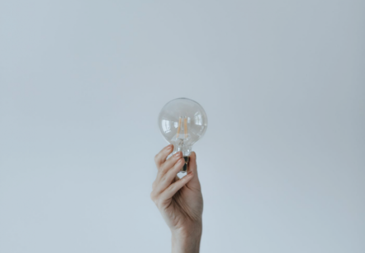 tech genius myth lightbulb being held in hand on plain white background 